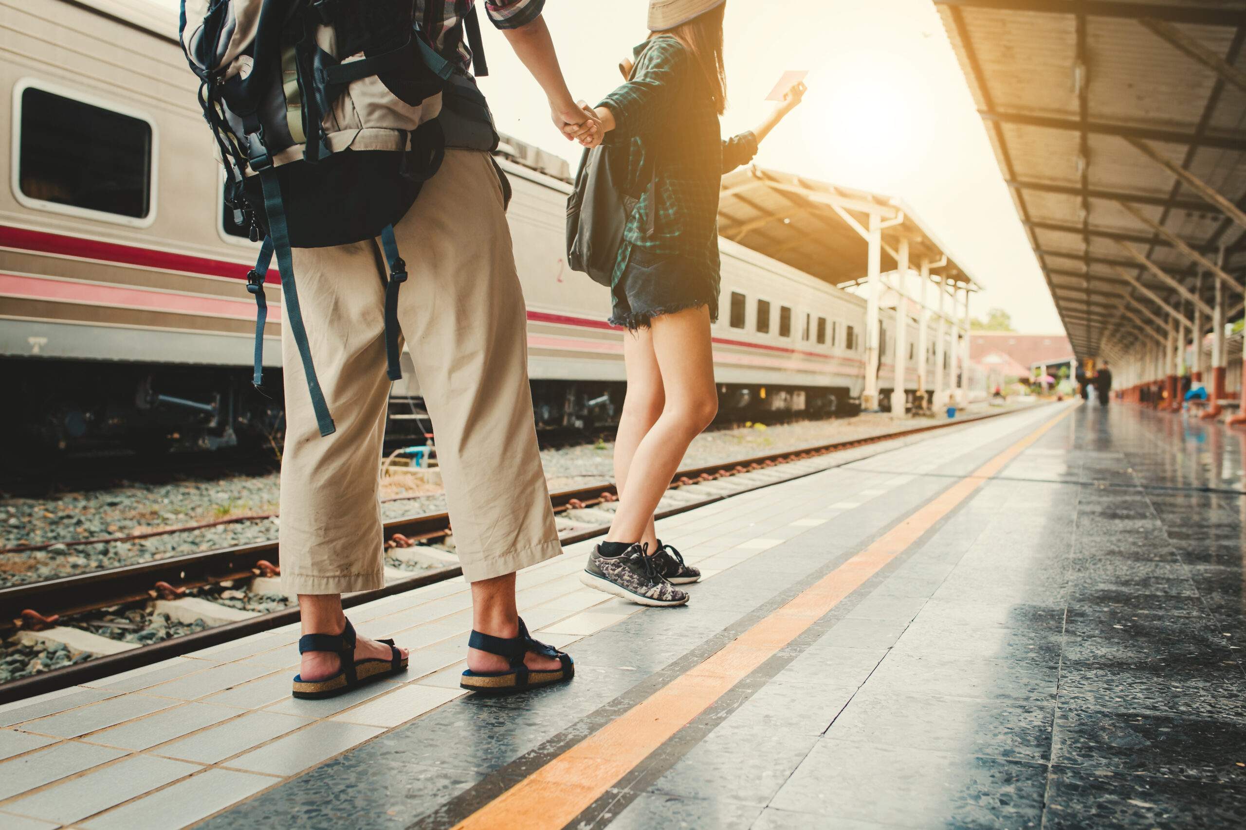 Man and woman holding hands at train station.
